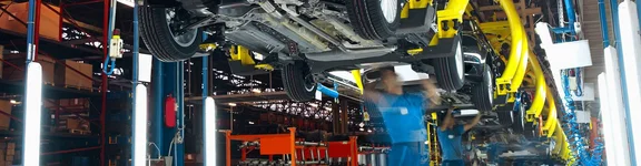 Ein Bild in einer Autofabrik, Männer unter hängenden Autos schrauben