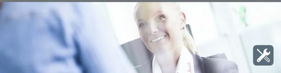 Eine lächelnde Frau sitzt im Büro einer Person gegenüber, die nicht erkennbar ist.